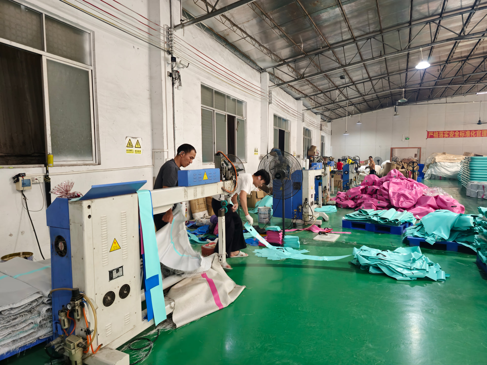 Real Air Track production workshop with workers, equipment, and inflatable materials